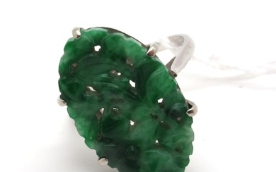 A Carved Oval Jade Panel Ring, claw set between plain should...