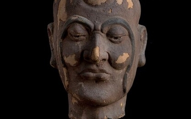 A Chinese clay head of a Luohan, Yuan/Ming dynasty, modelled and carved of a full rounded head with long sinuating eyebrows extending to his jawline, downcast eyes above a rounded nose, flanked by long pendulous earlobes, with a wood stand, 31cm...