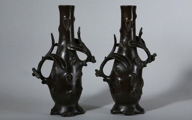 A PAIR OF CHINESE BRONZE 'PRUNUS TREE' VASES. Qing Dynasty. Each vase of slender form with a swelling body on an everted rim with a tall waisted neck further modelled as a burled trunk with a pair of handles cast in openwork as a branch each with two...