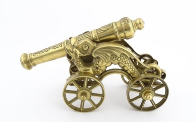 A brass ornamental cannon and wheeled carriage, the trunnion supports formed as dragons. Approx 16