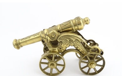 A brass ornamental cannon and wheeled carriage, the trunnion...