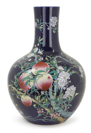 A large Chinese porcelain 'nine peaches' famille rose bottle vase, tianqiuping, Republic period, decorated with a leafy peach tree bearing nine fruit on a dark blue ground, apocryphal Qianlong seal mark to base, 55cm high