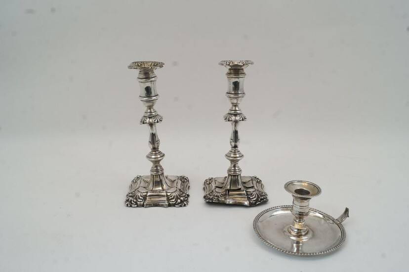 A pair of Edwardian silver candlesticks, Birmingham, 1900 and 1902, I S Greenberg & Co, damaged, with knopped stems on stepped foliate decorated bases, filled, 23cm high, together with a silver chamber stick, London, 1775, probably John Arnell...
