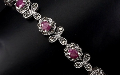 A ruby and marcasite bracelet set with four ovel-cut rubies and numerous circular-cut marcasites, mounted in rhodium plated sterling silver. L. 18 cm.