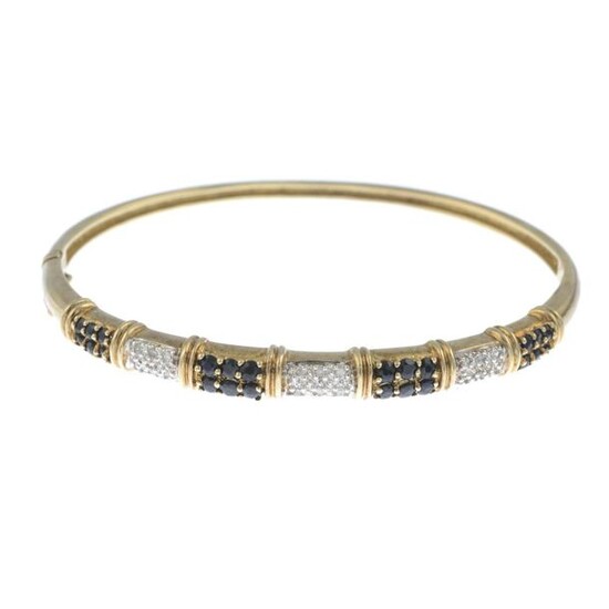 A sapphire and diamond bangle.Estimated total diamond weight 0.15ct. Inner diameter 6cms. 10.8gms.