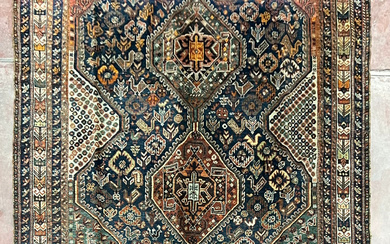 Tappeto Shiraz, Persia, inizio secolo XX. Decoro con tre medaglioni romboidali su fondo blu notte (cm 297x210) (difetti)