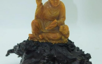 A Chinese soapstone carving of a scholar sitting on a
