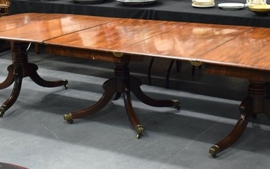 A FINE LARGE REGENCY CARVED MAHOGANY DINING TABLE with bronze capped supports, and two drop in leave