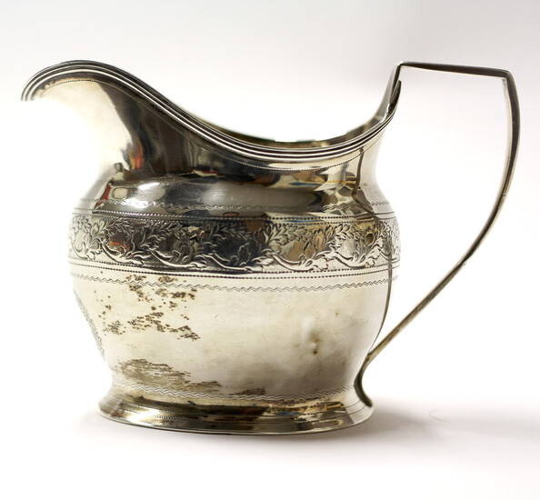 A George III silver cream jug, adorned with chased and engraved foliate band decoration