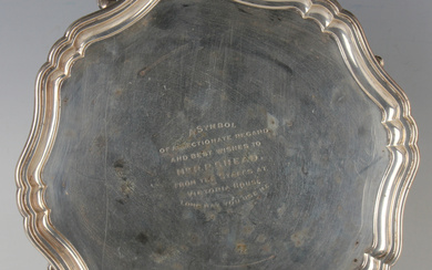 A George V silver circular card salver, presentation engraved, on scroll legs terminating in hoof fe