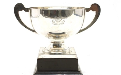 A George V silver twin handled trophy with scroll handles and square plinth base