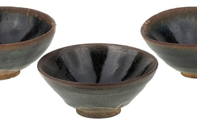 A group of three Chinese Jian ware tea bowls, Song dynasty, each of conical shape with deep sides rising from a short foot, covered in black glaze with hare fur pattern to rim, 9.2cm - 9.5cm diameter. (3) 宋 建盞一組三件