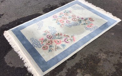 A rectangular Chinese wool rug with asymmetrical peony and blossom...