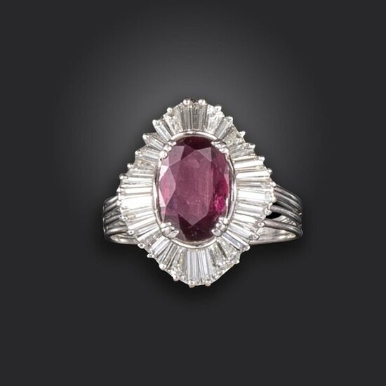 A ruby and diamond cluster ring, centred with an oval-shaped ruby weighing approximately 1.90cts, within ballerina mount set with tapered baguette-shaped diamonds in white gold, size R