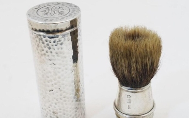 A silver cased travelling shaving brush, London, 1908, of planished cylindrical form with monogram to hinged top, the silver mounted brush is stored inside the tube and screwed to the body for use, 8cm high, weighable silver approx. 2.3oz