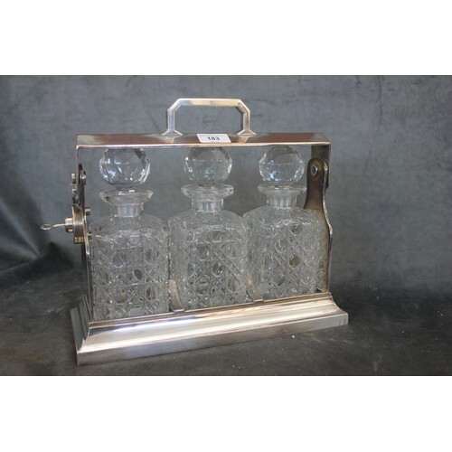 A silver-plated three bottle tantalus, with hob-nail decante...