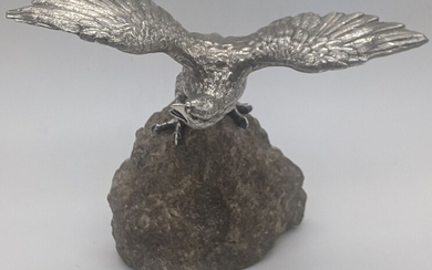 A silver sculpture of an eagle mounted on a...