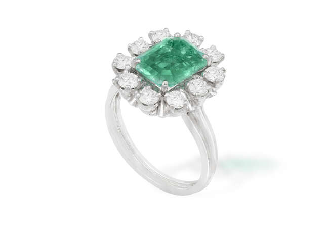 AN EMERALD AND DIAMOND CLUSTER RING The central...