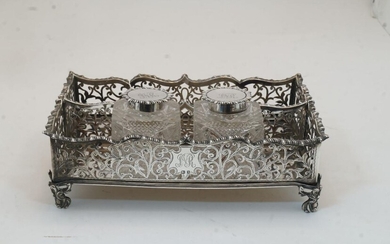 An Edwardian silver inkstand, Birmingham, 1907, Marston & Bayliss, with pierced scrolling foliate sides and serpentine gadrooned rims, on four scrolling foliate feet, with two silver mounted glass inkwells, the lids with gadrooned rims and engraved...