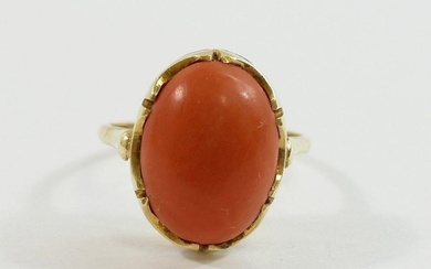 An oval coral cabochon in unmarked yellow metal ring mount, ...