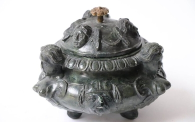 Green serpentine ointment jar carved with faces of...