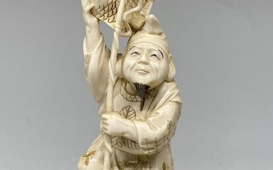 JAPON, c. 1930/1940. Okimono en ivoire sculpté, représentant un pêcheur debout sur un rocher, tenant...