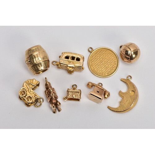 NINE 9CT GOLD CHARMS, to include a barrel, a hinged caravan,...