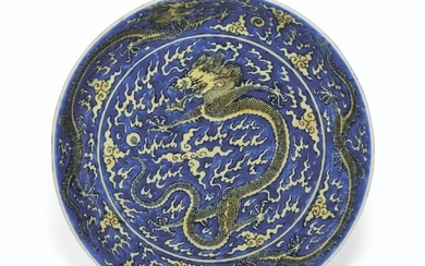 A YELLOW-ENAMELED BLUE-GROUND 'DRAGON' DISH, KANGXI SIX-CHARACTER MARK IN UNDERGLAZE BLUE WITHIN A DOUBLE CIRCLE AND OF THE PERIOD (1662-1722)