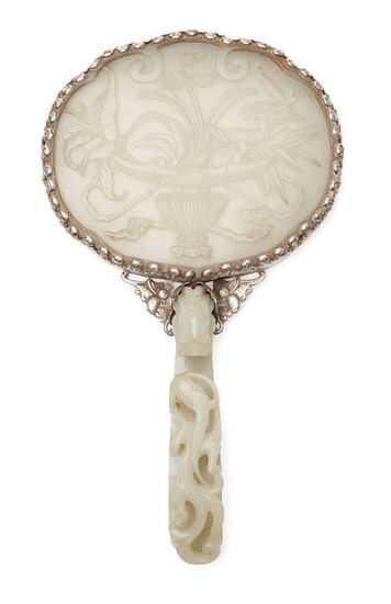 A Chinese greenish-white jade plaque and belt hook, 18th century, now mounted to form a hand mirror, the plaque finely carved in low relief with a basket issuing a peach and lingzhi fungus sprigs, 10.5cm x 13cm, the belt hook finely carved with...