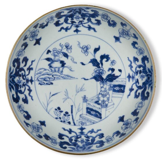 A Chinese porcelain blue and white 'peonies' dish, 18th century, painted with flowering peony blossoms amongst leafy stems issuing from a vase, the outer border decorated with lotus blooms and peony blossoms, 23cm diameter