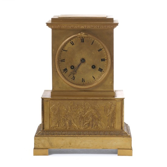 A French Empire gilt bronze mantel clock with Roman numerals in black, the base with classis figures in relif. Early 19th century. H. 31 cm. W. 22 cm. D. 13 cm.