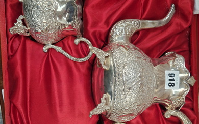 A RED CASED GERMAN SILVER THREE PIECE TEA SET, EACH PIECE CHASED WITH FLOWERS