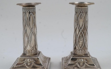 A pair of Edwardian Adam Revival silver candlesticks, London, 1901, Thomas Bradbury & Sons, of columnar form with beaded edges and chased with rams heads and swags, filled, 13.5cm high (2)