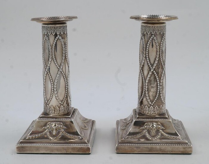 A pair of Edwardian Adam Revival silver candlesticks, London, 1901, Thomas Bradbury & Sons, of columnar form with beaded edges and chased with rams heads and swags, filled, 13.5cm high (2)