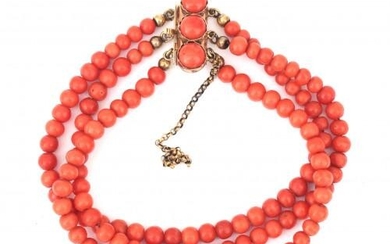 A precious coral bracelet to a 14 karat gold clasp. Three strands of round coral beads, to a rectangular tongue clasp with three coral boutons. Gross weight: 22 g.