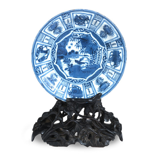 A very well-carved dense blackwood 'lotus pond' plate stand displaying a 'Kraak porcelain'-style saucer dish