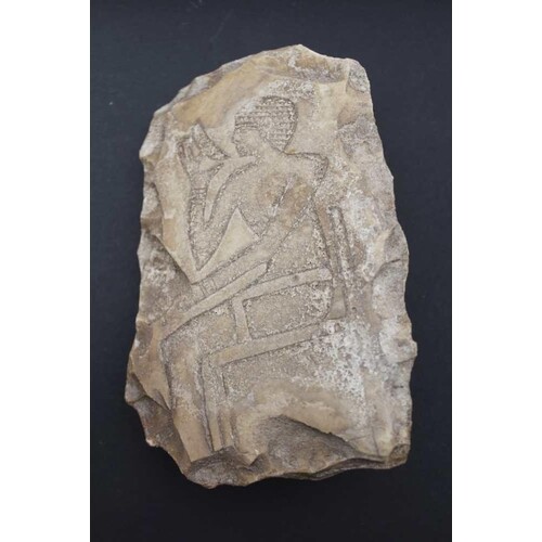 AN EGYPTIAN LIMESTONE FRAGMENT relief carved with a seated f...