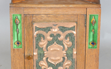 An Edwardian Arts and Crafts oak hanging corner cabinet, possibly by Liberty & Co, the door inse