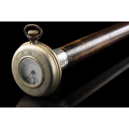 An early 20th-century beechwood walking stick with silvered metal handle enclosing a silver "American Waltham USA" pocket watch (1920 circa)....