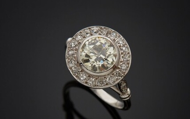 Bague en or gris 18K 750‰, de forme ronde, ornée en son centre d’un diamant...