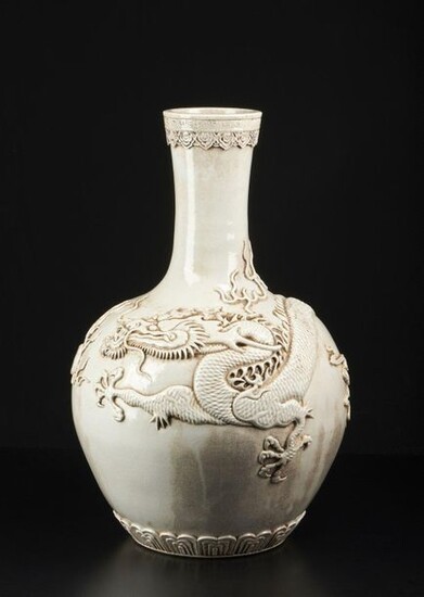 Chinese Art. A large white porcelain vase with applied decoration depicting a dragon chasing the flaming pearl China, early 20th century . Long inscription and mark at the base. Cm 35,00 x 62,00.