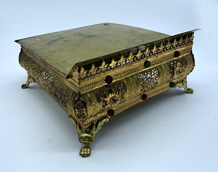 THABOR forming MISSEL HOLDER in bronze and gilt metal. It rests on four lion paw legs, it is openworked with foliage and set with cabohons of coloured glass. The top is decorated with a cross in a quatrefoil. 15.5 x 28 x 31 cm.