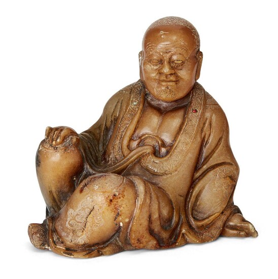 A Chinese soapstone carving of a Luohan, 18th/19th, century, finely carved in a seated pose with serene expression, his robes finely incised with decorative motifs and inset with three coral and turquoise beads, the underside incised with clouds...