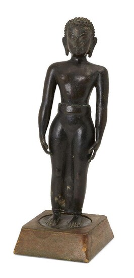 A Jain bronze figure of Tirthankara, South India, 17th century or earlier, on a flat, round base, standing with arms at his side in the tadasana pose, a serene expression on his face and with hair in tight sculpted curls, on a square wood base...