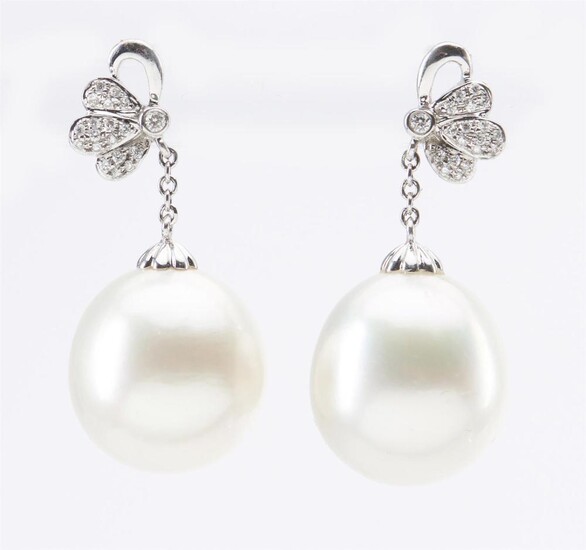 A PAIR OF SOUTH SEA PEARL AND DIAMOND EARRINGS - Each earring comprising a round pearl of silver white hues measuring 13.2mm, suspen...