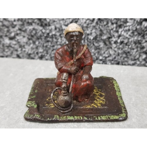 A cold painted bronze figure of an arab smoking a hookah pip...