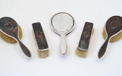 A five piece tortoiseshell and silver vanity set, Birmingham, 1916-1917, Mappin & Webb, comprising two clothes brushes, a hair brush, and a hand mirror, together with a matching hair brush, Birmingham, 1917, makers mark rubbed (5)