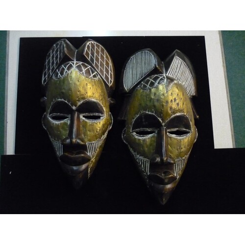 A pair of African tribal masks with engraving to the hairpie...