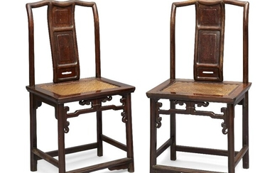 A pair of Chinese hongmu chairs, 18th / early 19th century, the shaped top rails above serpentine back splats, each inset with three carved burwood panels, the rattan seats supported by ruyi shaped ornamental stretchers, 94cm high. (2) 十八/十九世紀早期...