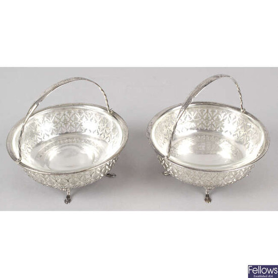 A pair of George V silver pierced swing-handle dishes with glass liners.